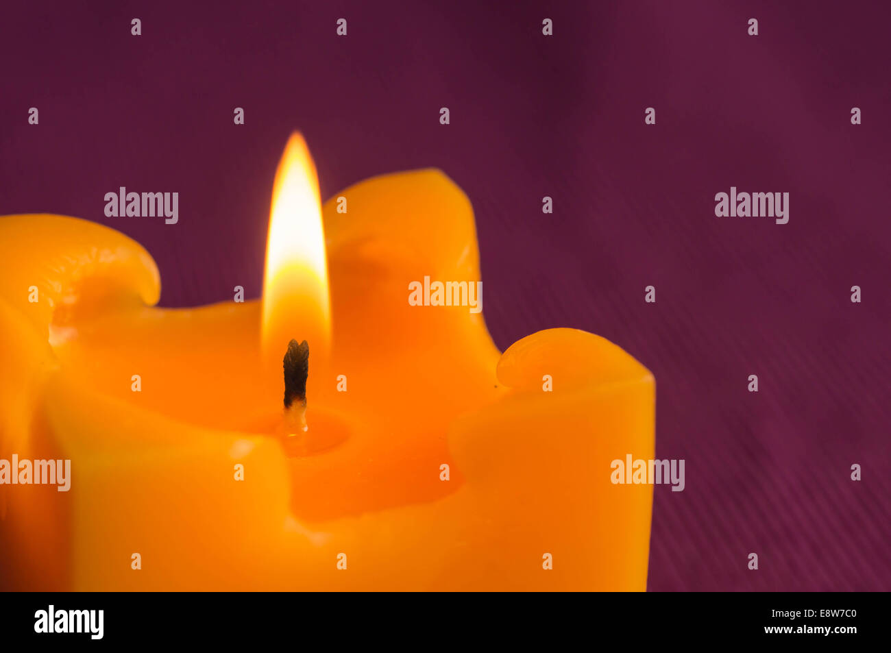 Burning yellow candle on a crimson background Stock Photo Alamy
