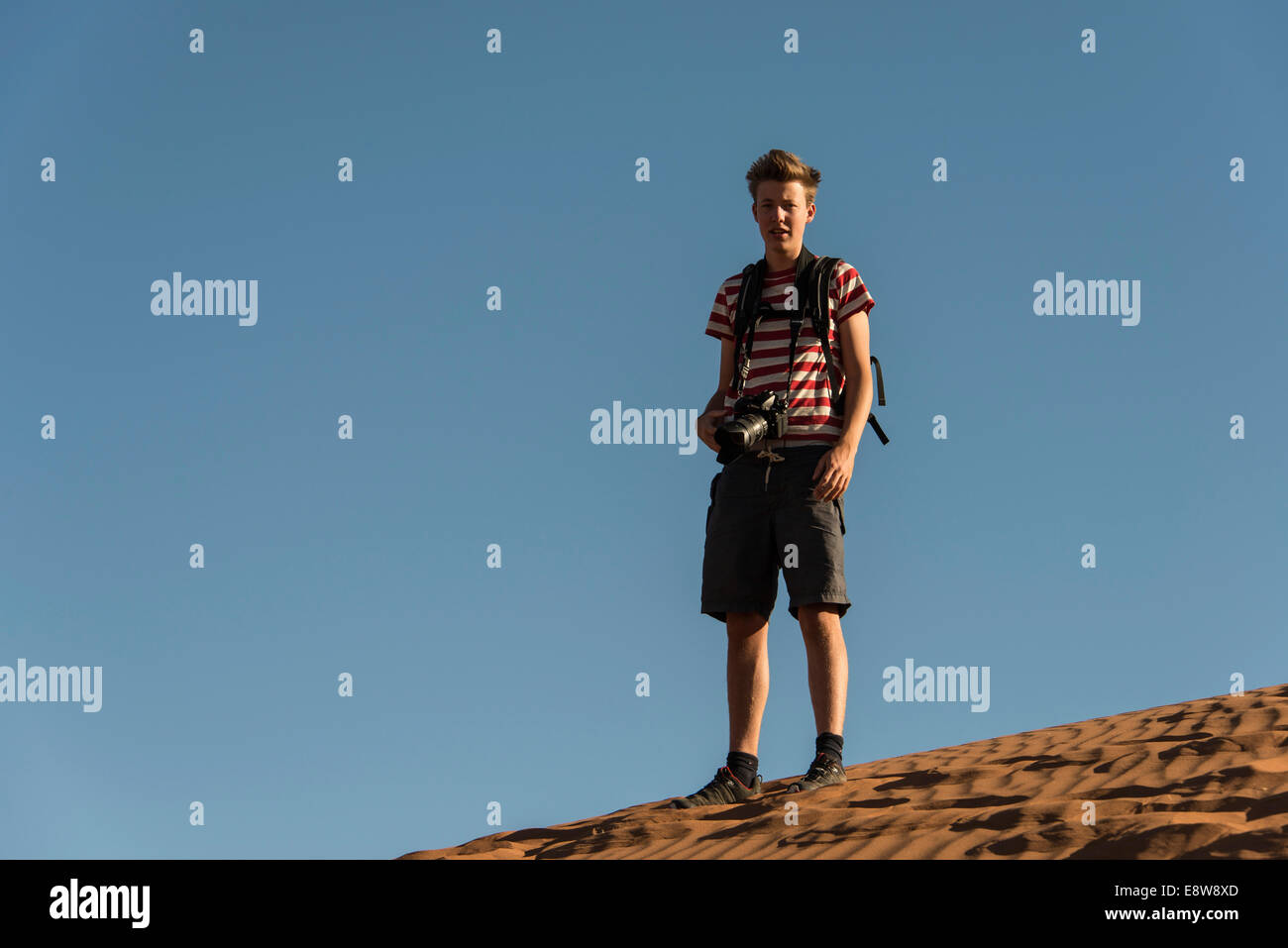 Teenager with photo camera standing on a dune, Sossusvlei, Namib Desert, Namibia Stock Photo