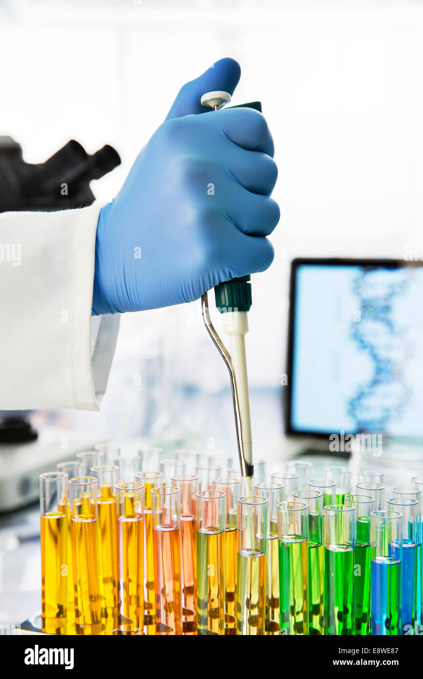 Close up of scientist pipetting solution into test tubes in lab Stock Photo