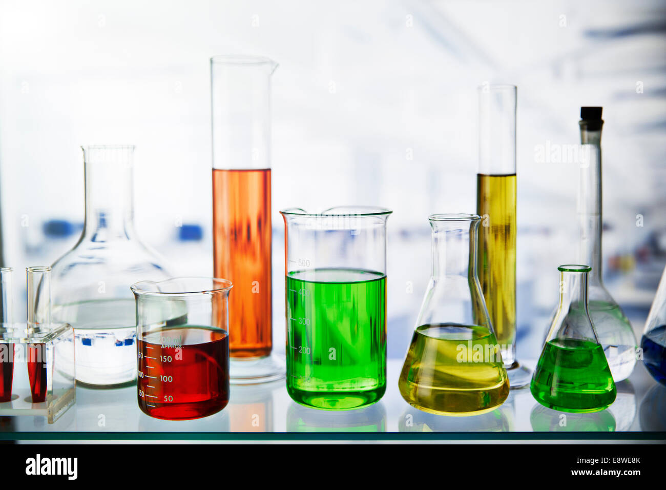 Beakers of various solutions on shelf in lab Stock Photo