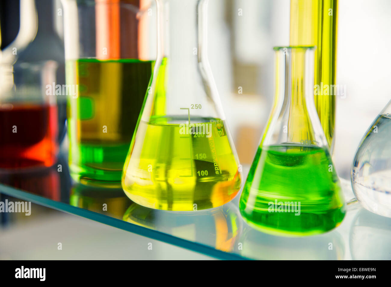 Close up of beakers with solutions on shelf in lab Stock Photo