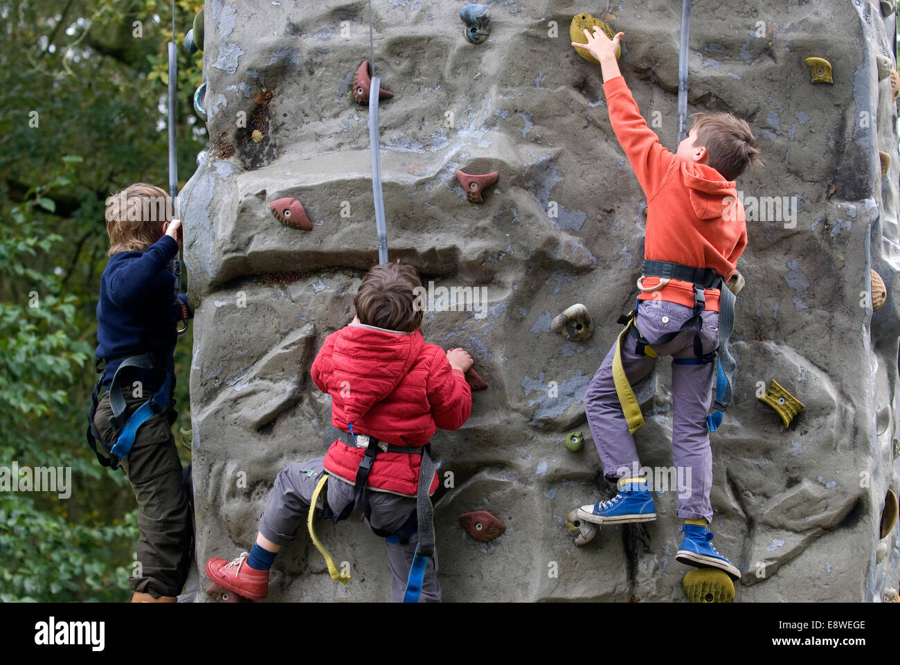 Three kids attempting the climbing wall at a farm open day, Blackmoor, Hampshire, UK. Stock Photo