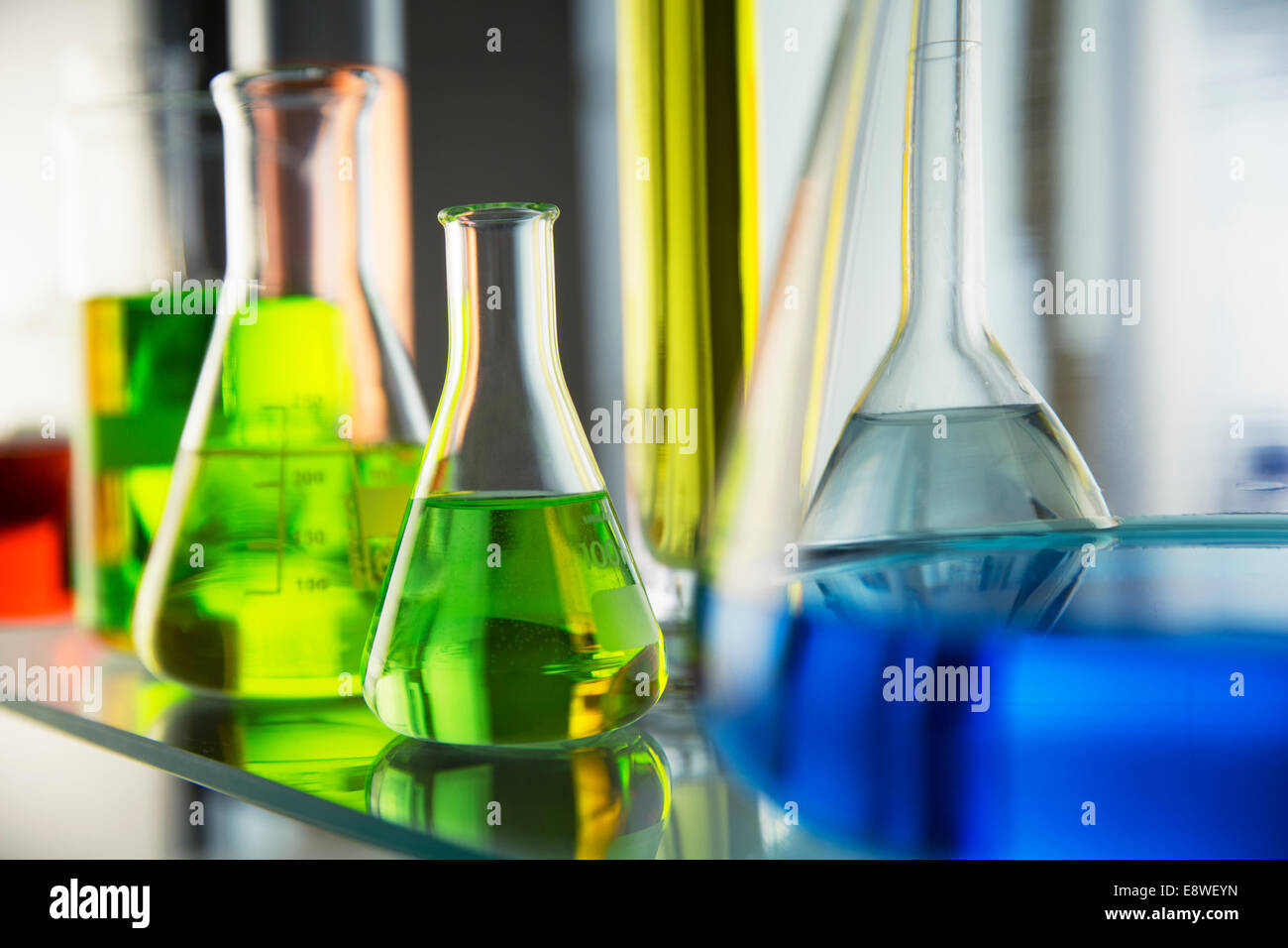 Close up of beakers with solutions on shelf in lab Stock Photo