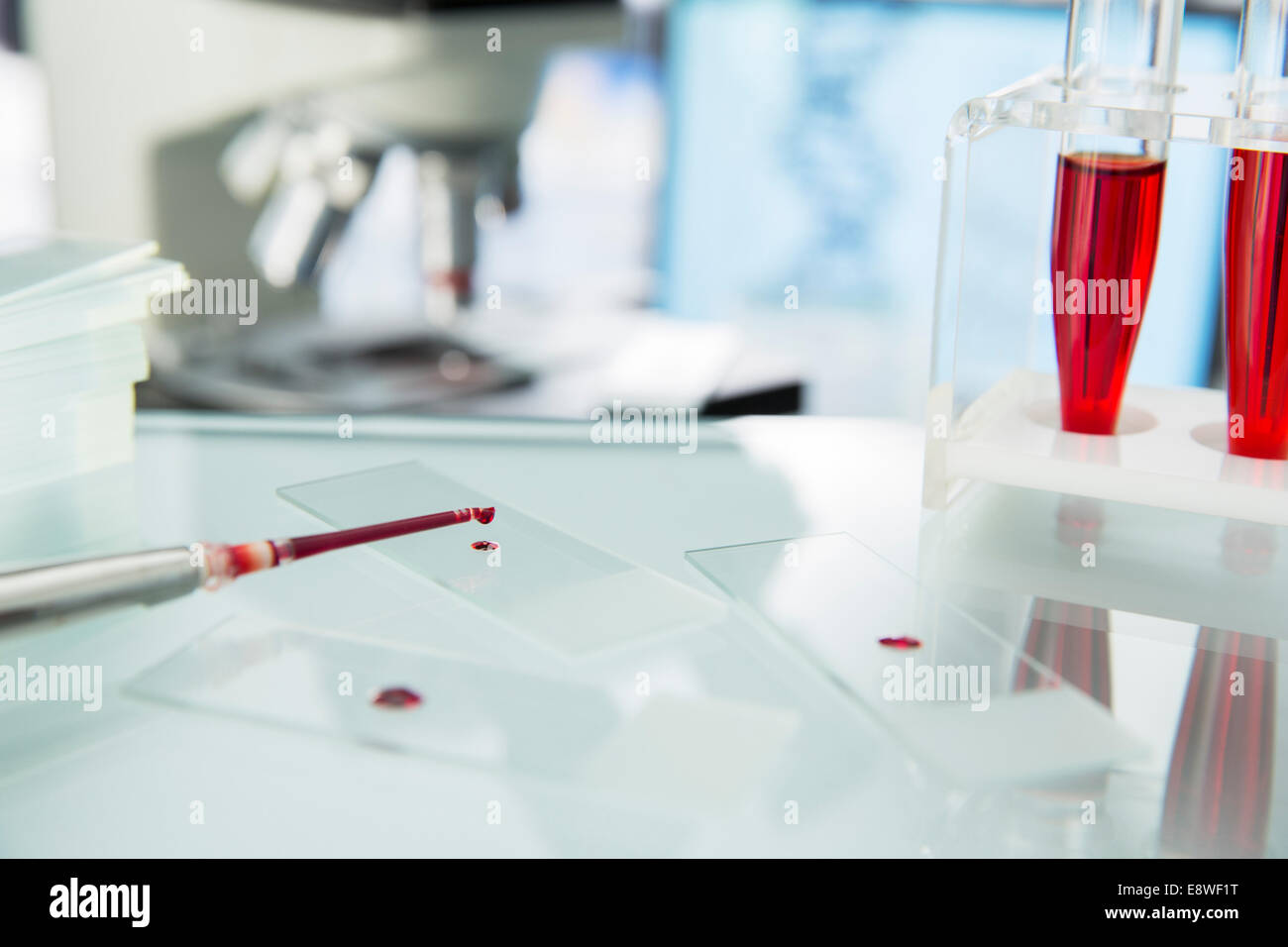 Close up of pipette dropping sample onto microscope slide in lab Stock Photo