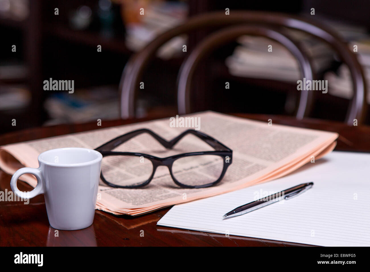 Newspapers and coffee cup, reading glasses, pen and striped paper Stock