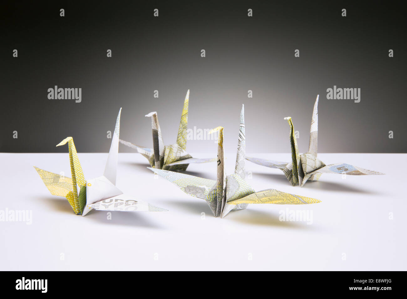 Origami cranes made of Euros on counter Stock Photo