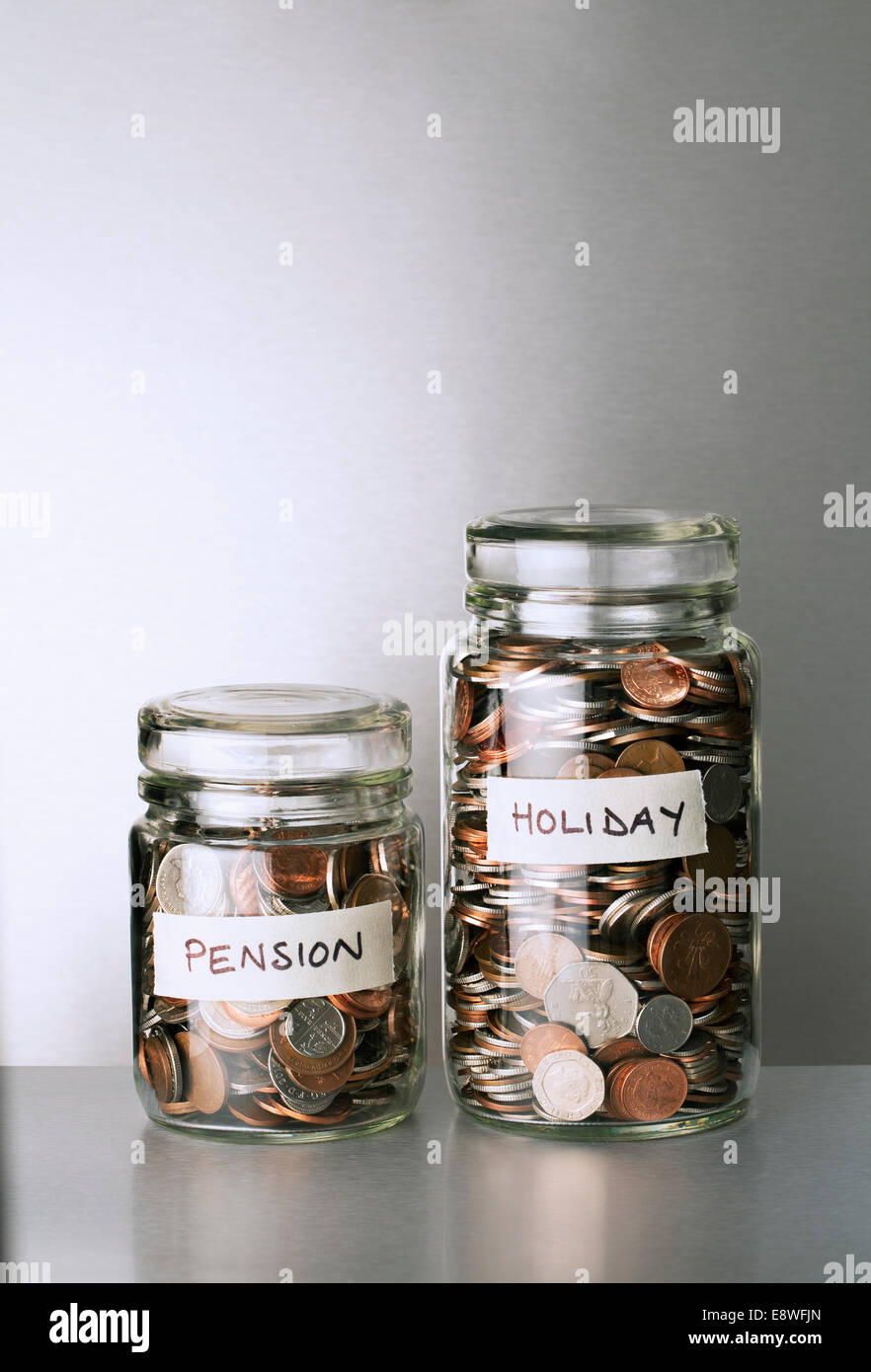 Pension and holiday change savings jars on counter Stock Photo