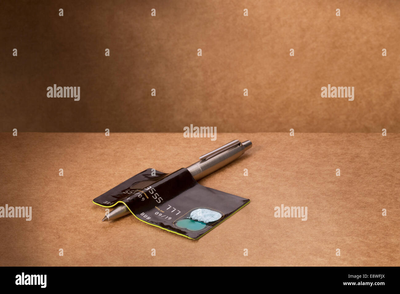 Credit card bent over pen on counter Stock Photo