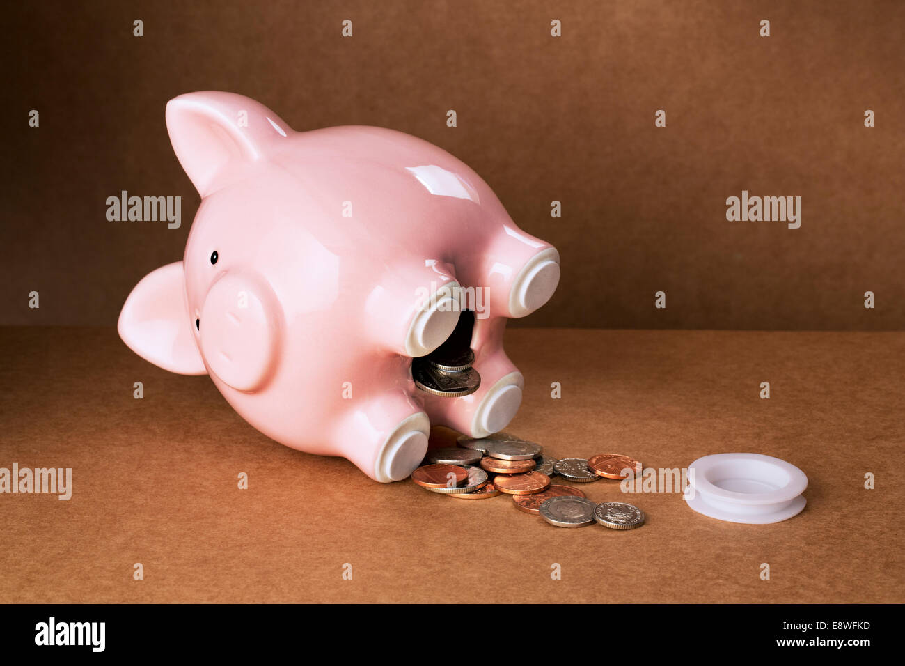 Piggy bank spilling out change onto counter Stock Photo
