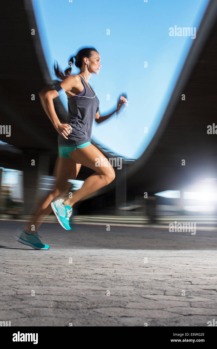 Woman running through city streets Stock Photo
