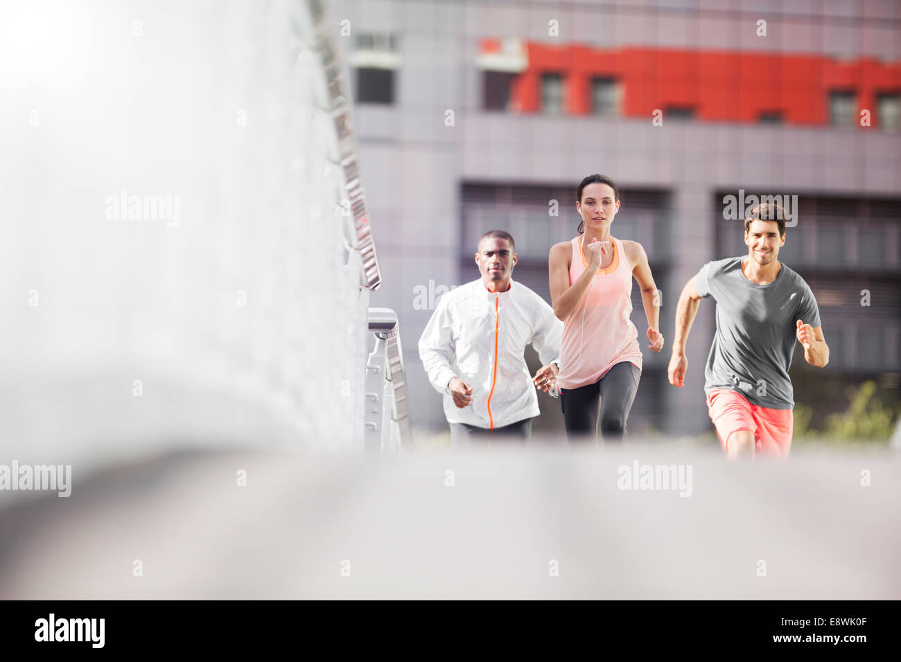 Friends running through city streets together Stock Photo