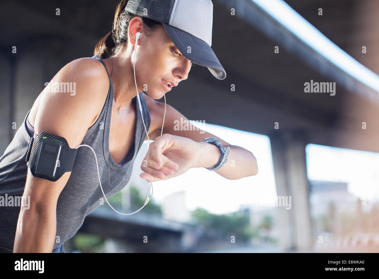 Woman looking at watch after exercising on city street Stock Photo