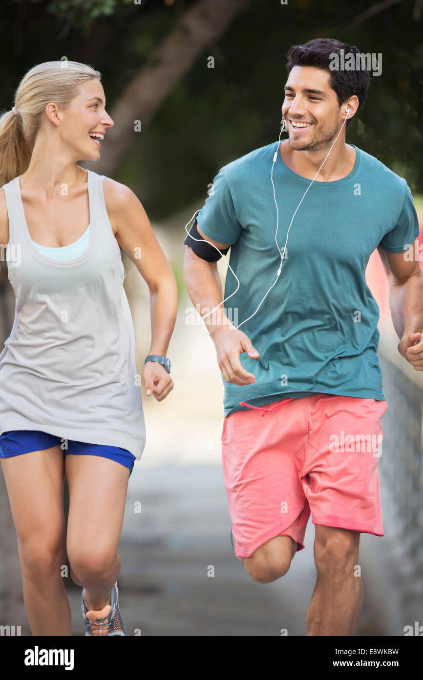 Couple running through city streets together Stock Photo