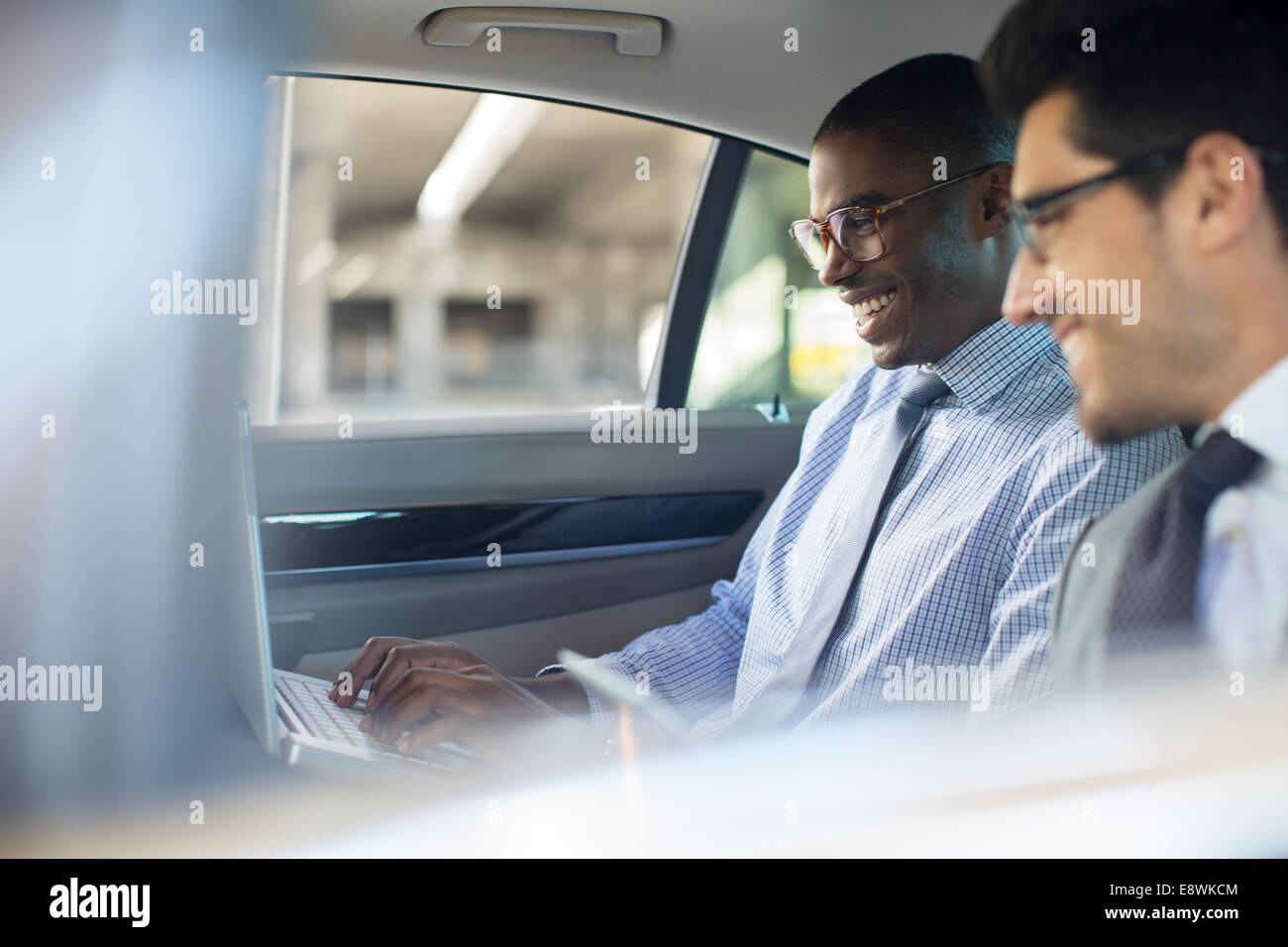 Businessmen using laptop in car Stock Photo