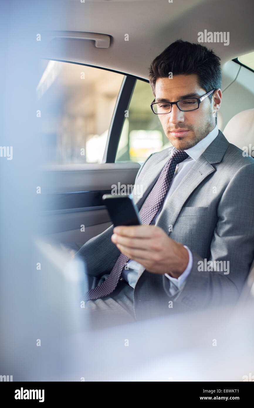 Businessman using cell phone in car back seat Stock Photo