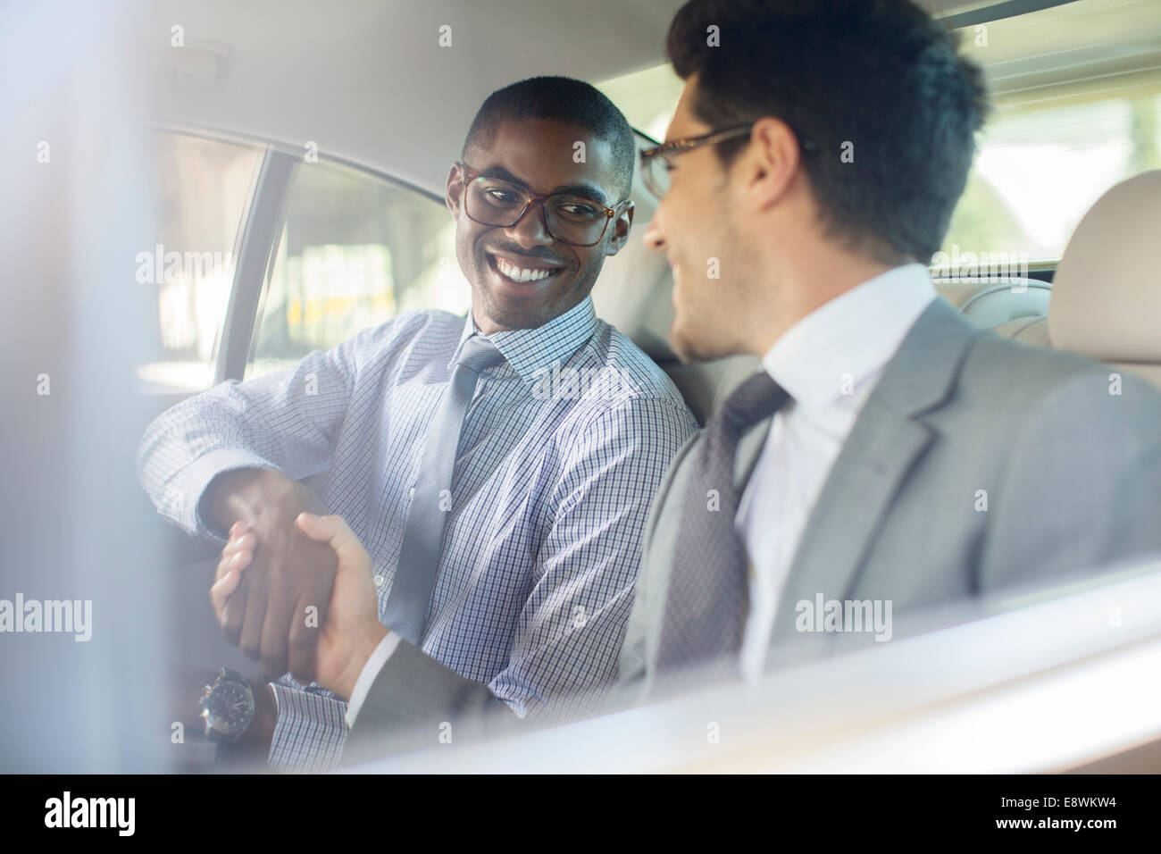 Smiling businessmen shaking hands in car Stock Photo