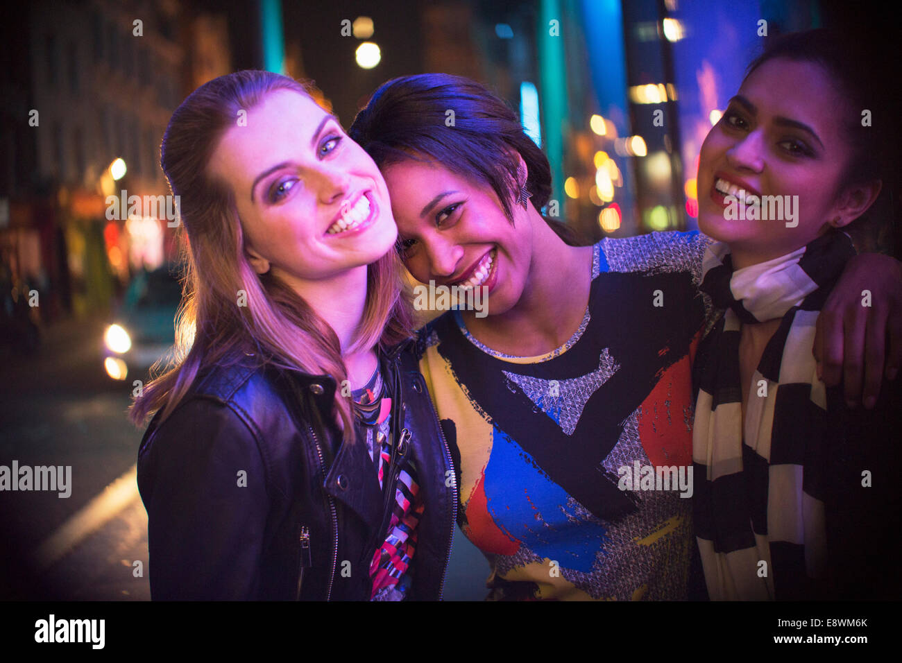 Women smiling together outside of store at night Stock Photo