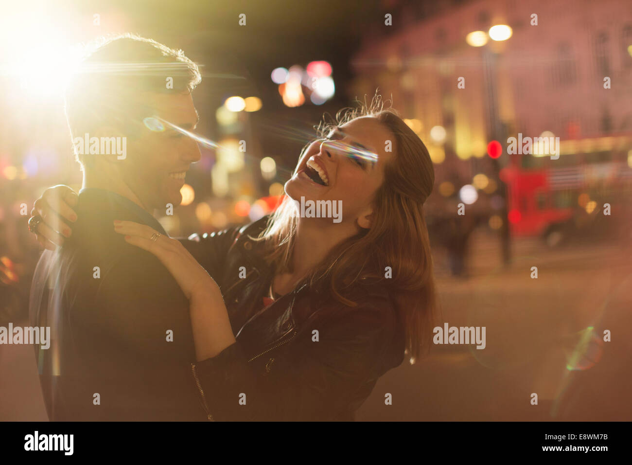 Couple hugging on city street at night Stock Photo