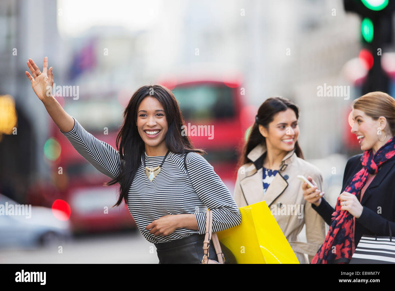 Woman calling taxi with friends on city street Stock Photo