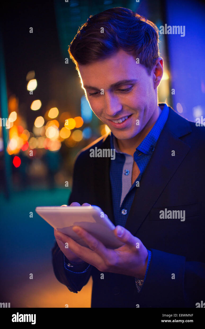 Man using digital tablet on city street at night Stock Photo - Alamy