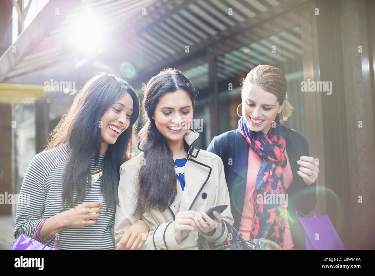 Women looking at cell phone on city street Stock Photo