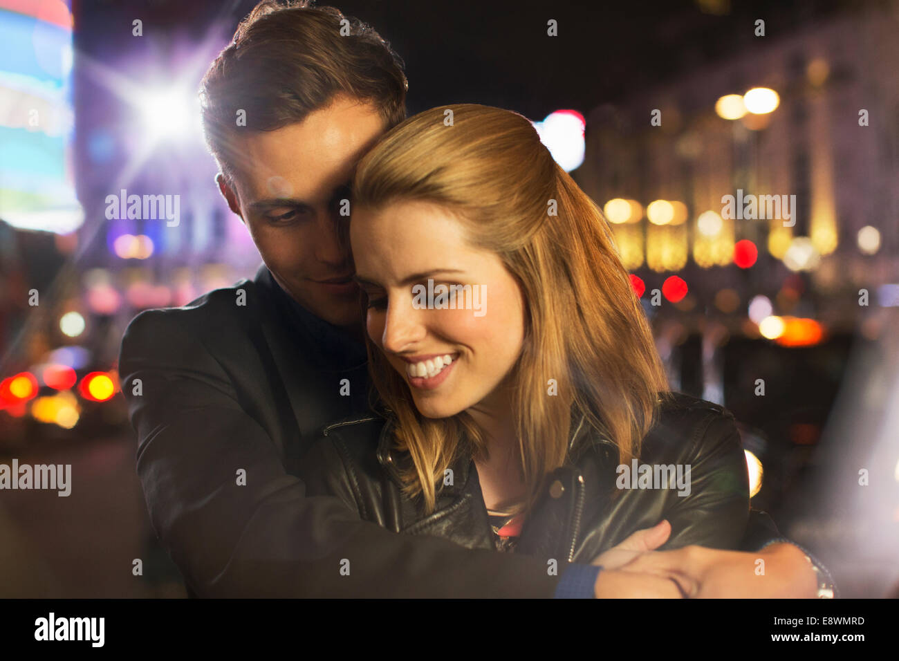 Couple hugging on city street at night Stock Photo