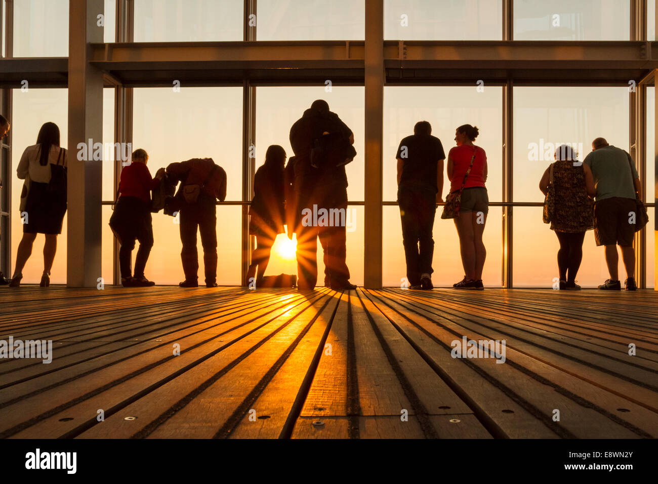 Silhouettes of people against the evening sky and sun while looking out through windows from the interior and top of The Shard, London, England, UK Stock Photo