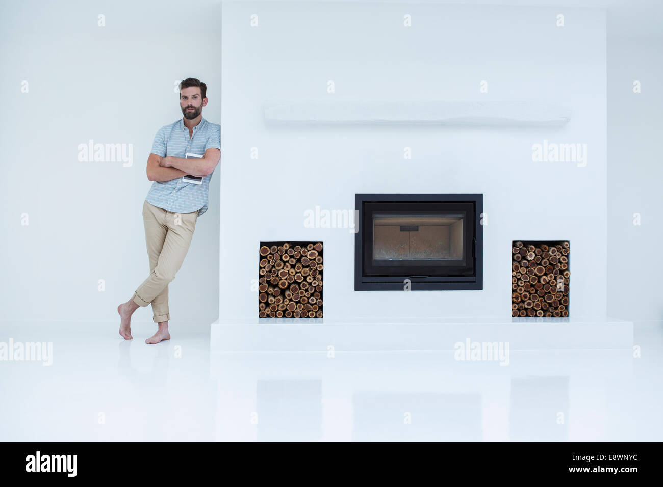 Man leaning on modern fireplace Stock Photo