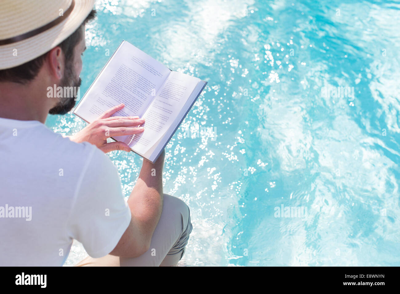 Man reading book over swimming pool Stock Photo