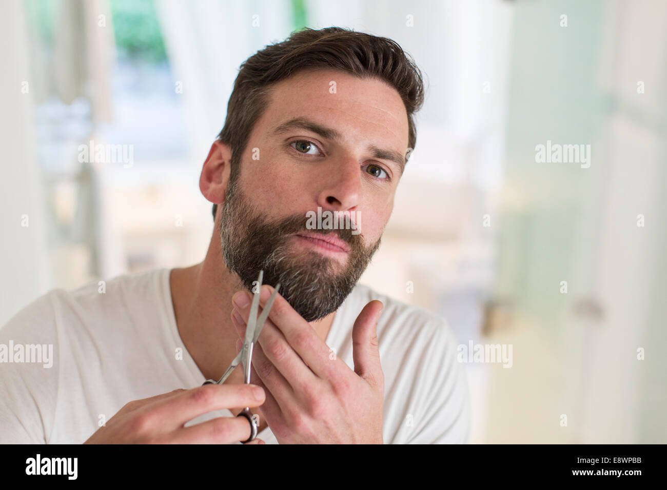 Man trimming beard in bathroom Stock Photo