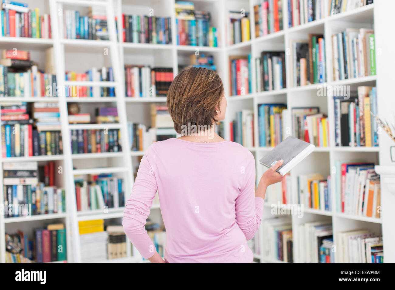 Woman selecting book from library Stock Photo