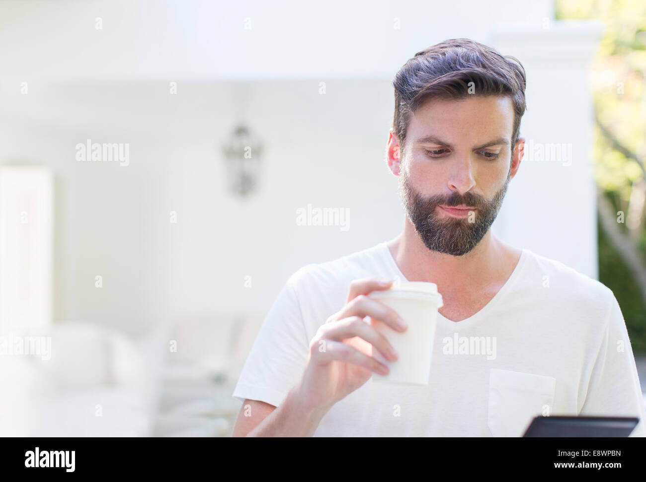 Man drinking coffee and using digital tablet Stock Photo