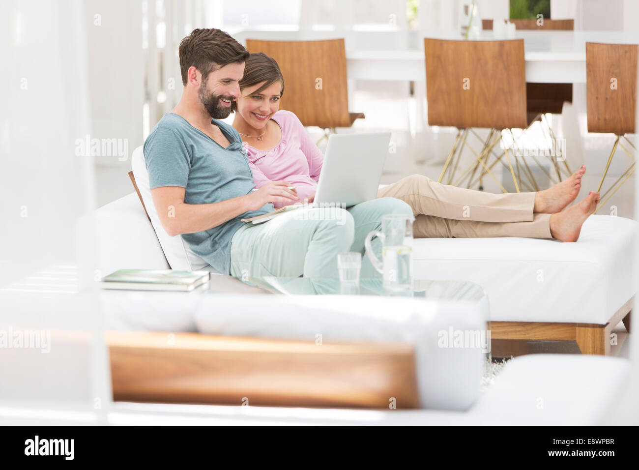 Couple using laptop together on daybed in modern living room Stock ...
