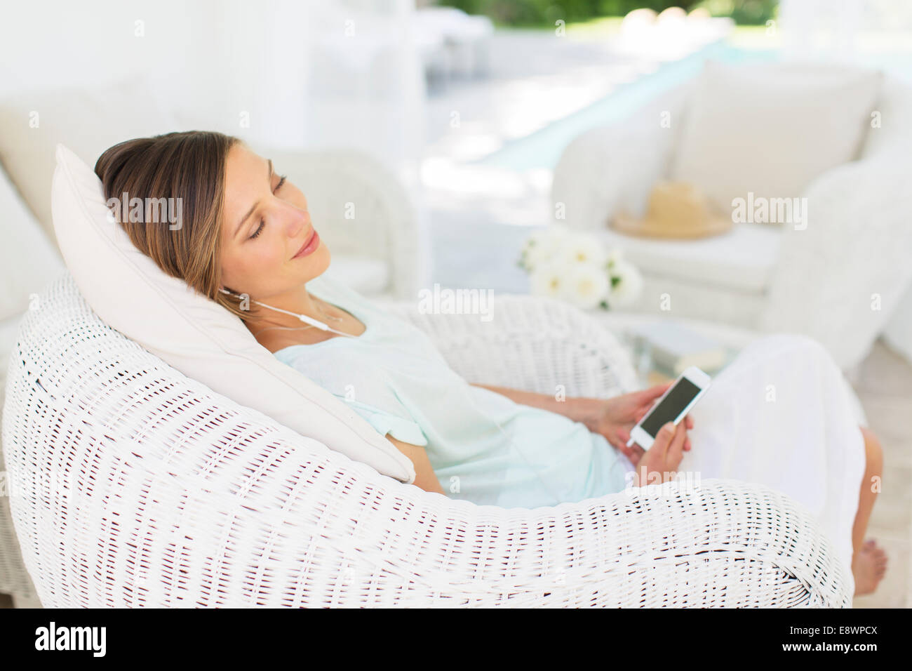 Woman listening to music in wicker chair Stock Photo