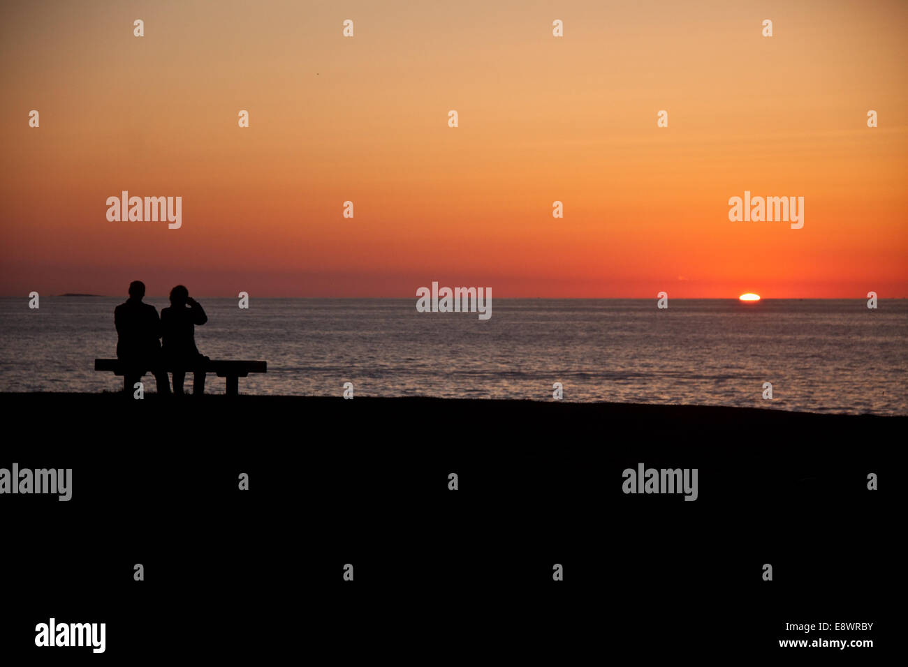 Two people watching the sunrise over the Atlantic Ocean near the ...
