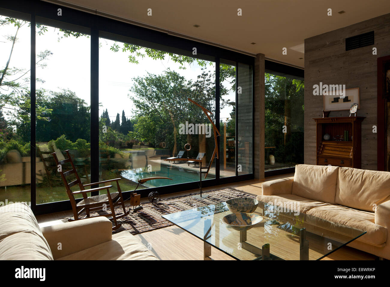 Cream sofas and glass topped coffee table with full length windows in