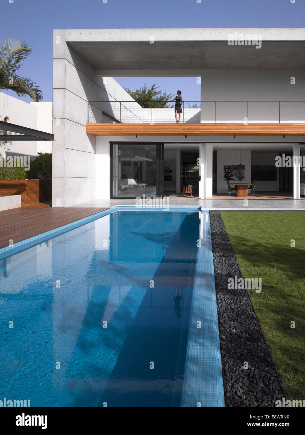 Woman stands on double height balcony facade of D House with swimming