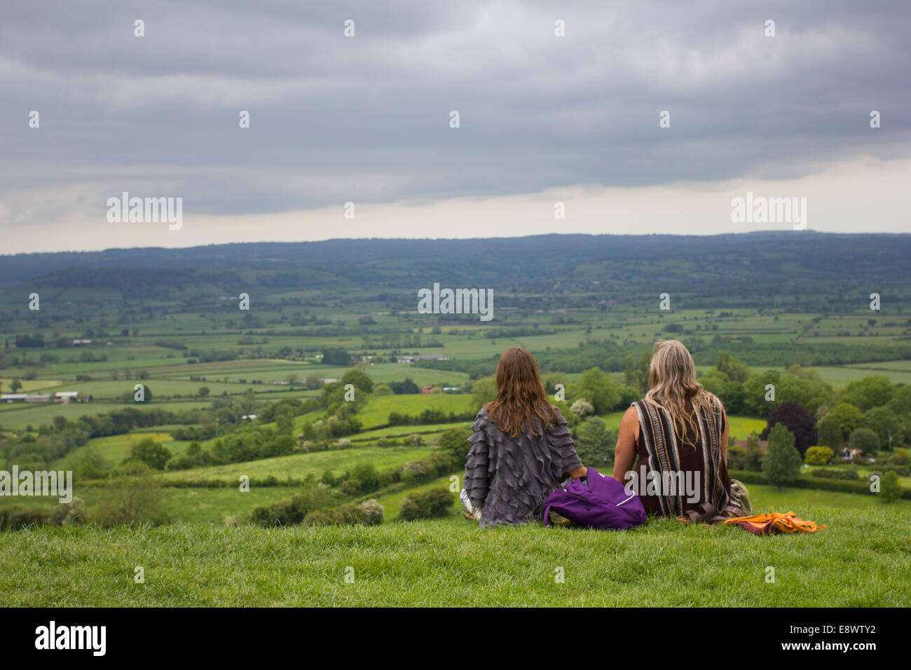 Man and woman sitting down admiring the view from Glastonbury tor, Somerset, England, UK Stock Photo