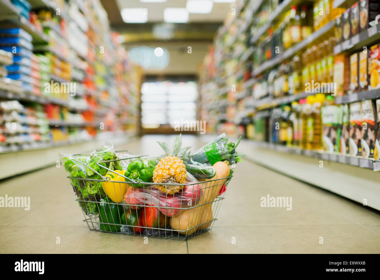 Close up of full shopping basket on floor of grocery store Stock Photo