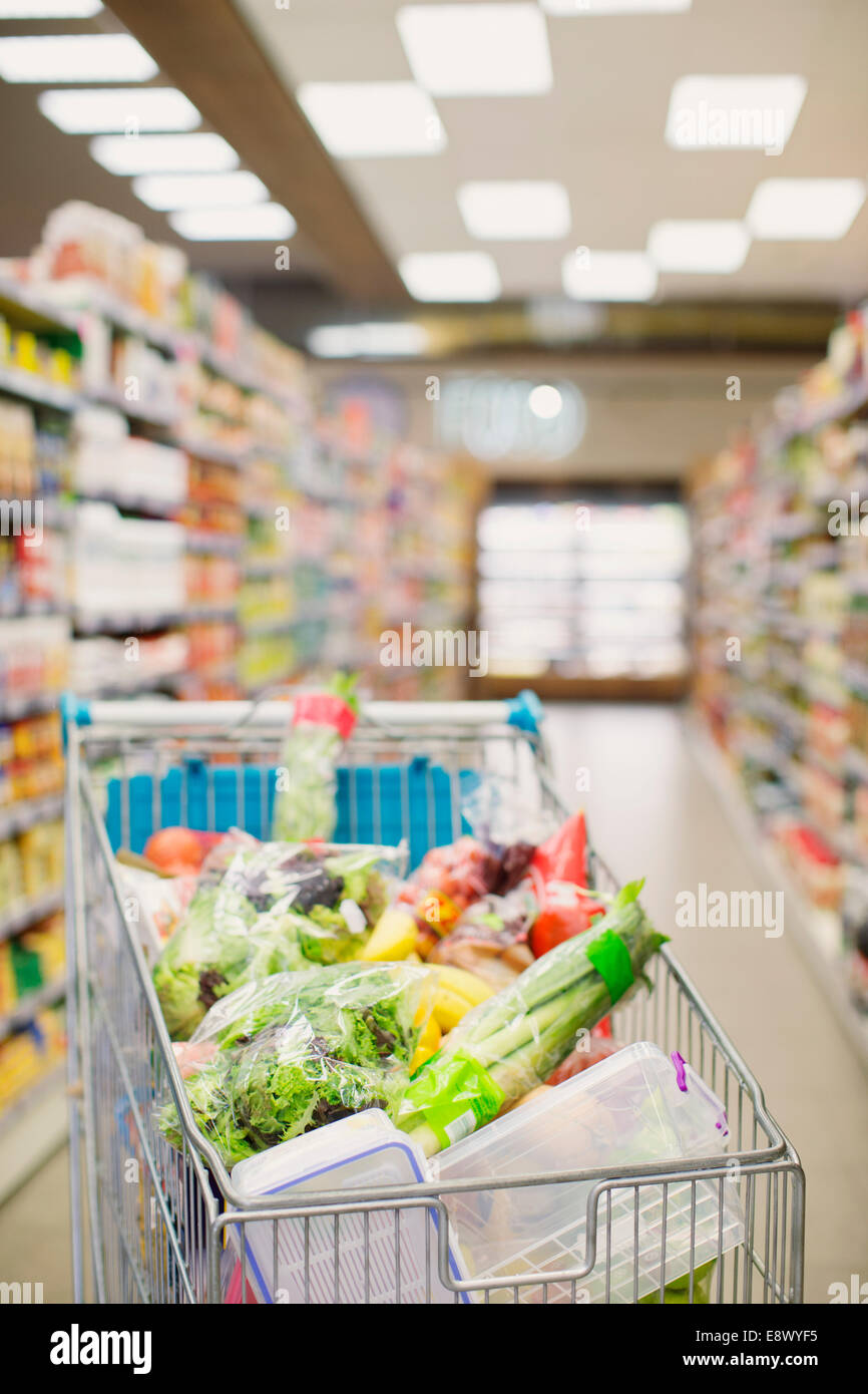 Full shopping cart in grocery store aisle Stock Photo