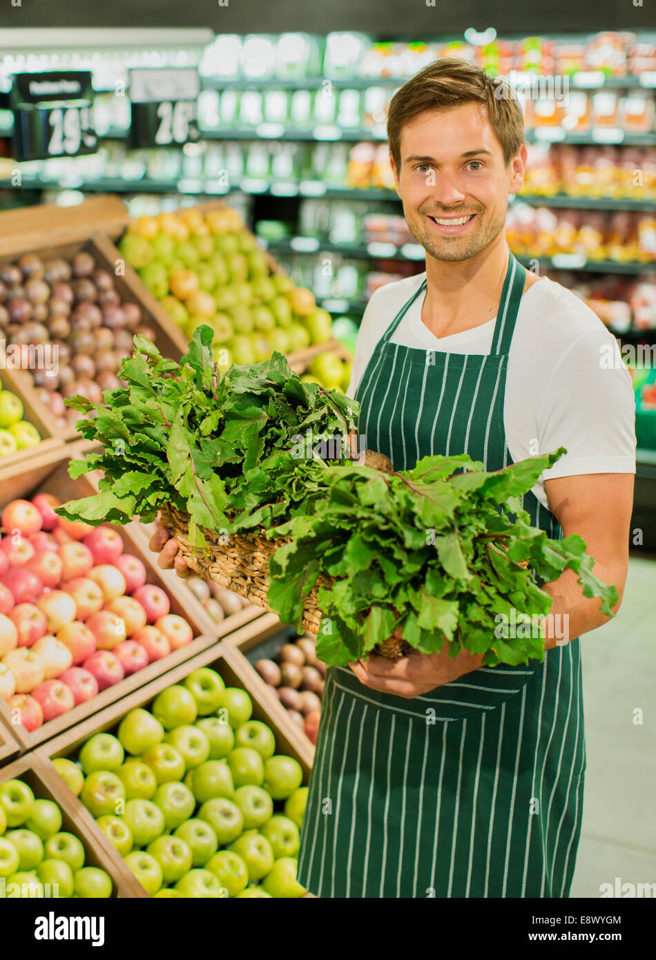 https://c8.alamy.com/comp/E8WYGM/clerk-carrying-basket-of-produce-in-grocery-store-E8WYGM.jpg