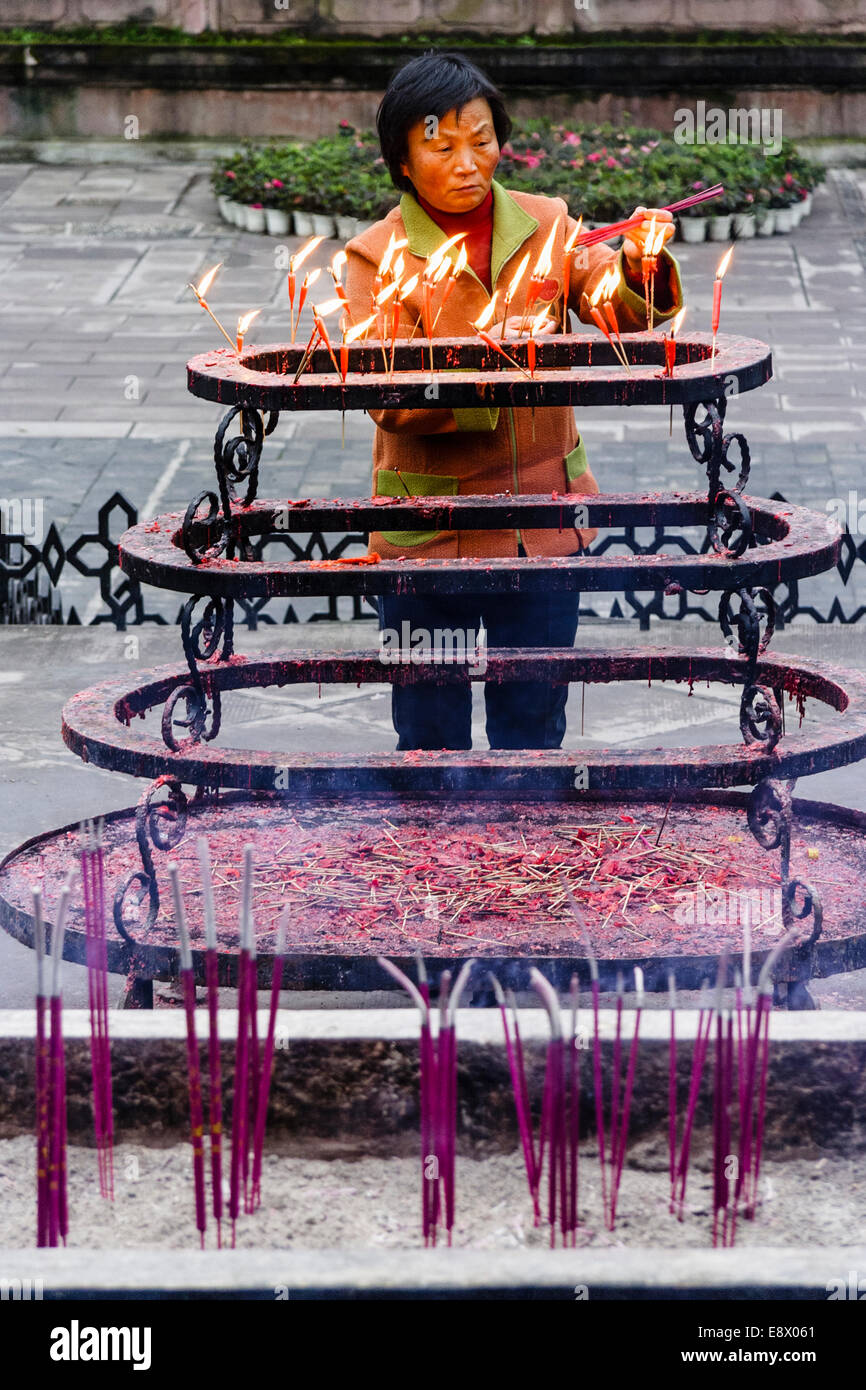 Chinese woman lighting candles at Qingyang Taoist Temple. Chengdu, Sichuan, China Stock Photo