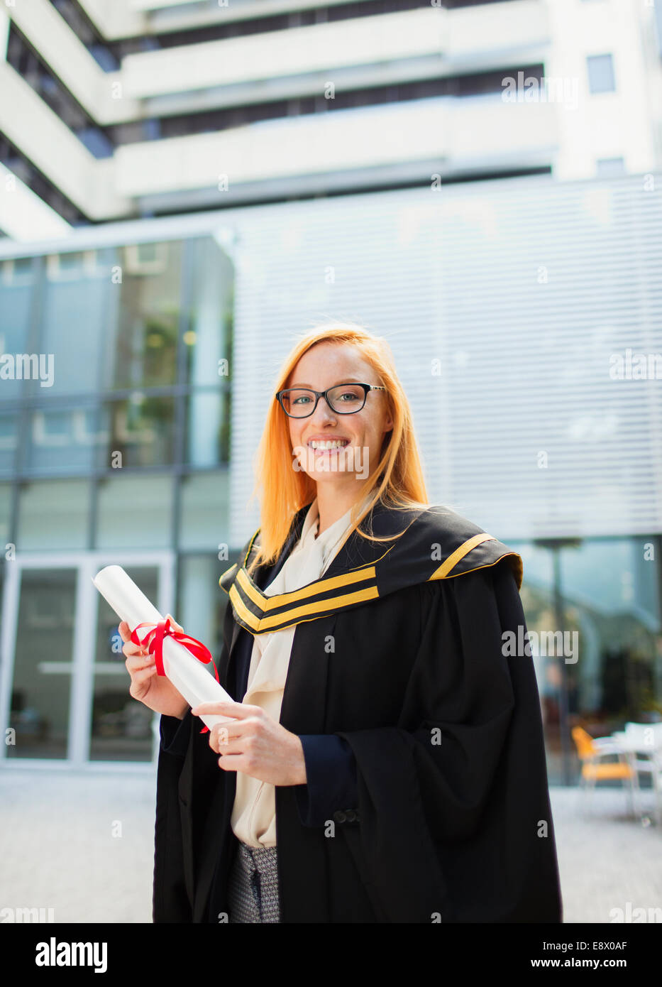 Student in cap and gown holding scroll Stock Photo