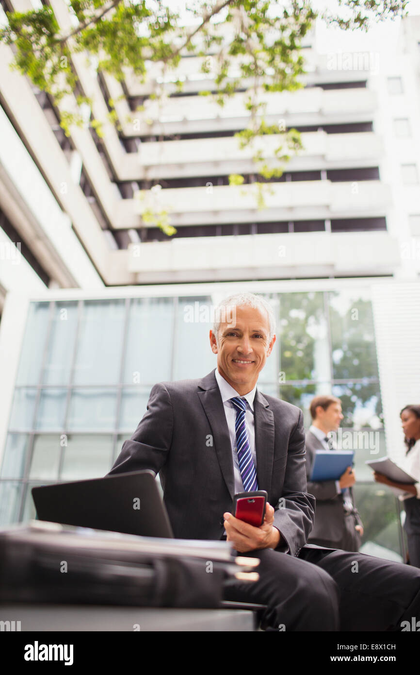 Businessman working on bench outside of office building Stock Photo