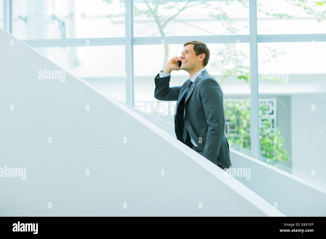 Businessman talking on cell phone on stairs of office building Stock Photo