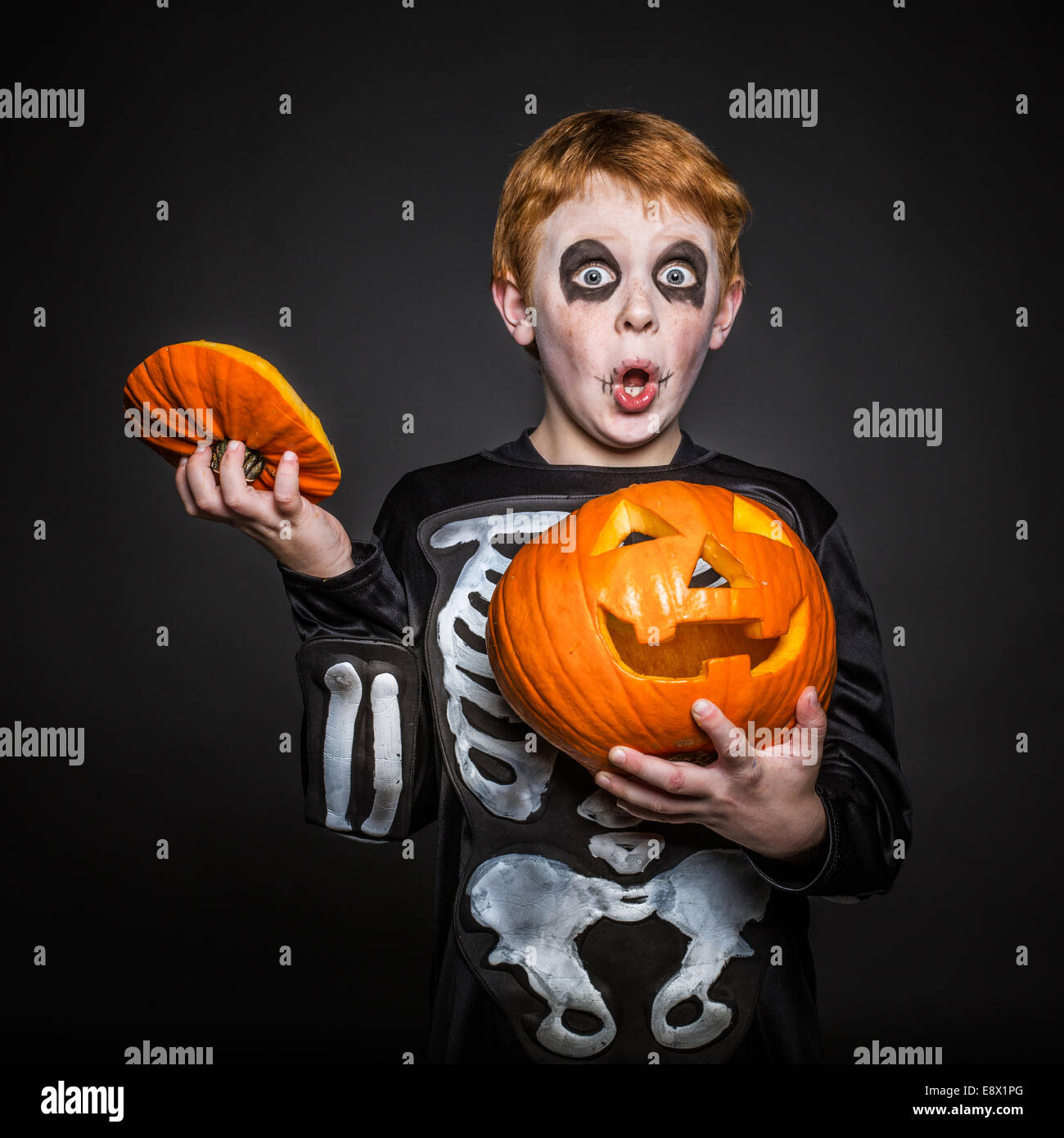 Surprised red hair kid in Halloween costume holding a orange pumpkin.  Skeleton Stock Photo - Alamy