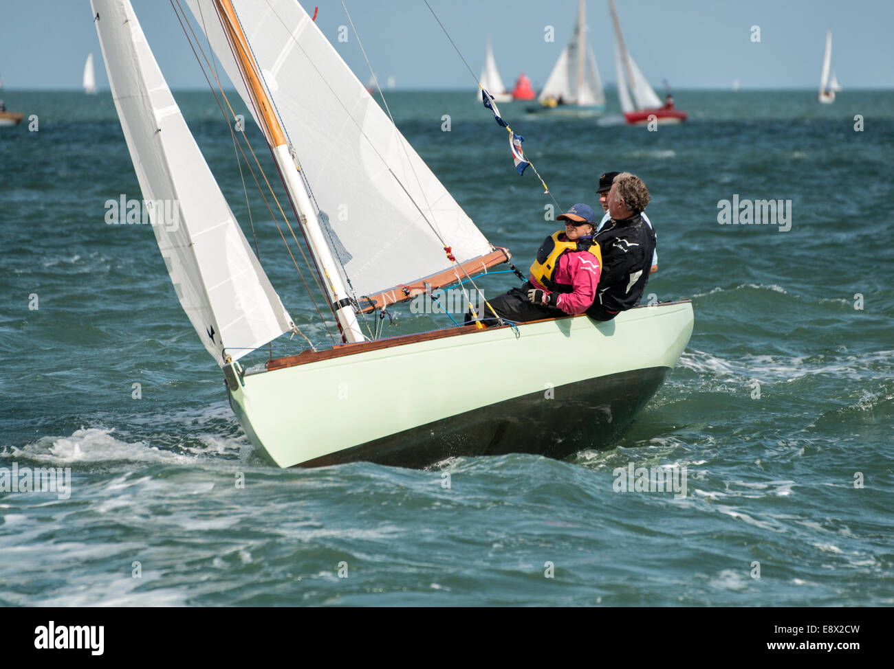 These three sailors are enjoying racing their sailing dinghy in the Solent during the Cowes week regatta. Stock Photo