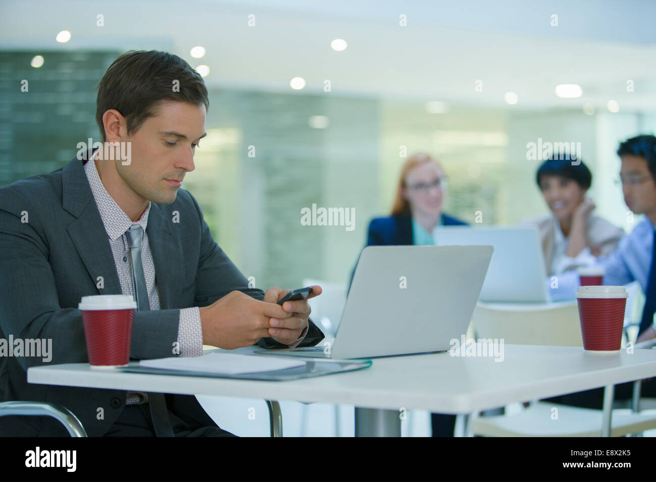 Businessman using cell phone in office building cafe Stock Photo