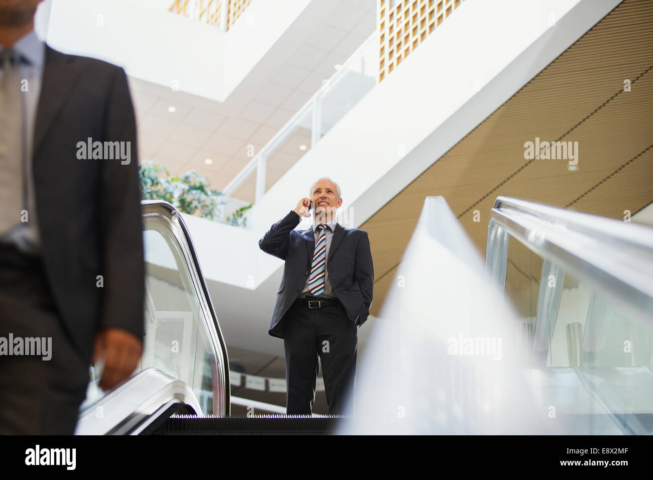 Businessman talking on cell phone at top of stairs in office building Stock Photo