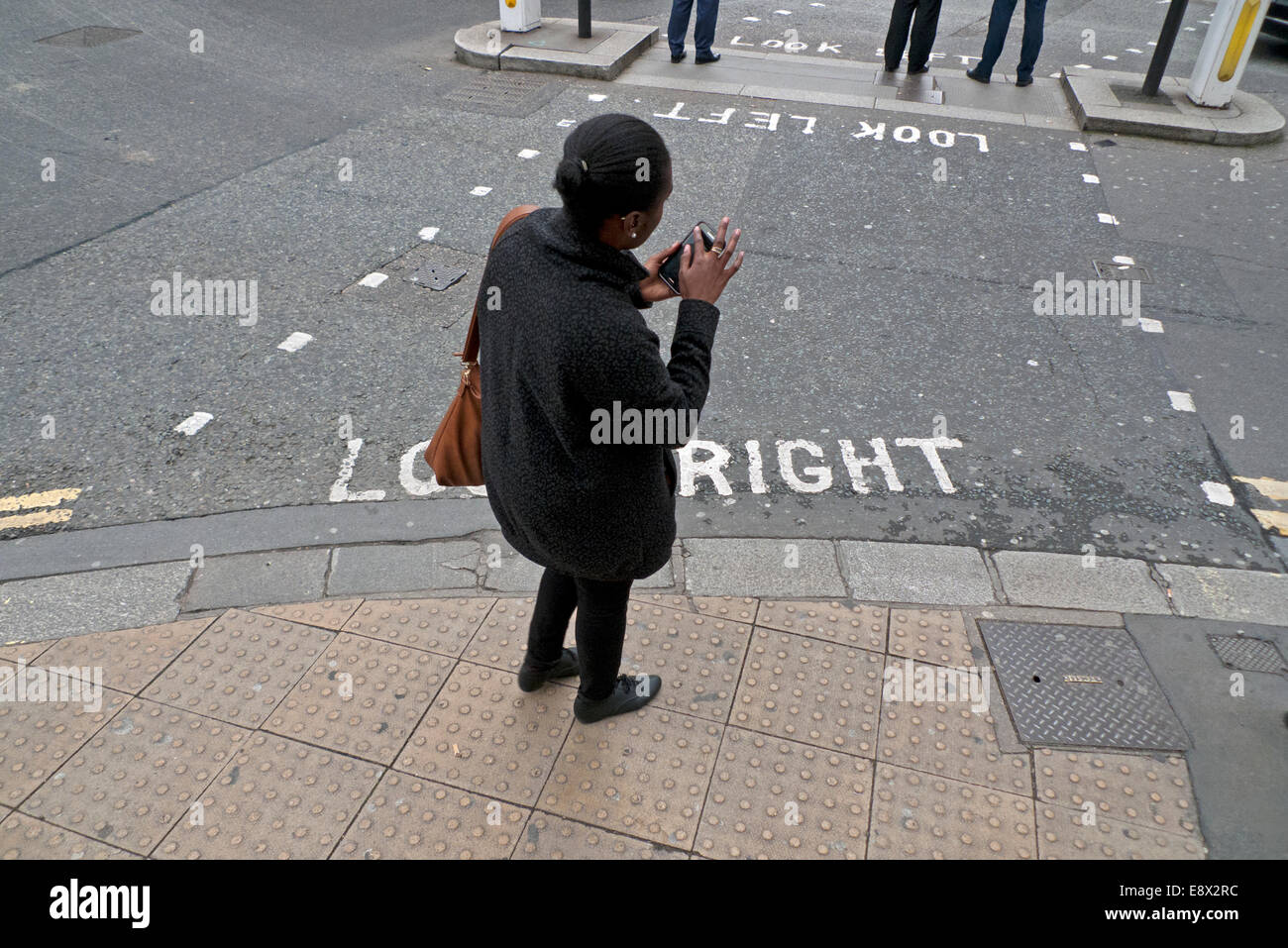 Man on mobile phone cross the road at a pedestrian crossing. Ho